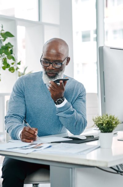 dl.beatsnoop.com-1645702546 Shot of a mature businessman talking on a cellphone while writing notes in an office